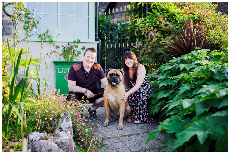 couple posing with their dog outside their home before photography session