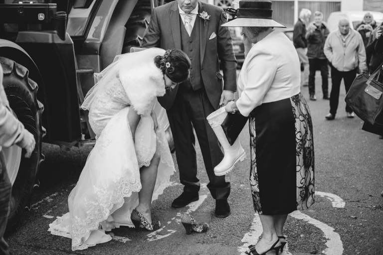 bride changing wellies for heels outside st saviours church dartmouth