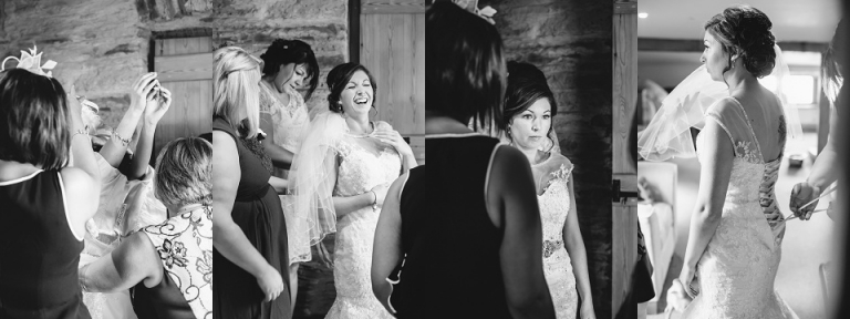 black and white photography of bridesmaids helping bride put on her wedding dress and lacing her up