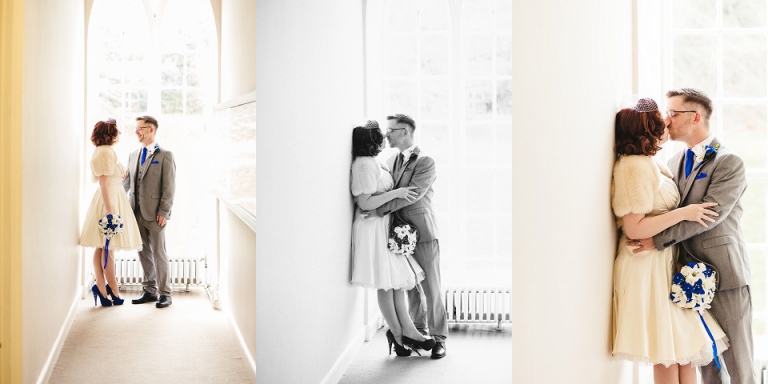 beautiful light in portrait of eloped couple in front of window at cockington court torquay, bride leaning against wall, husband kiss