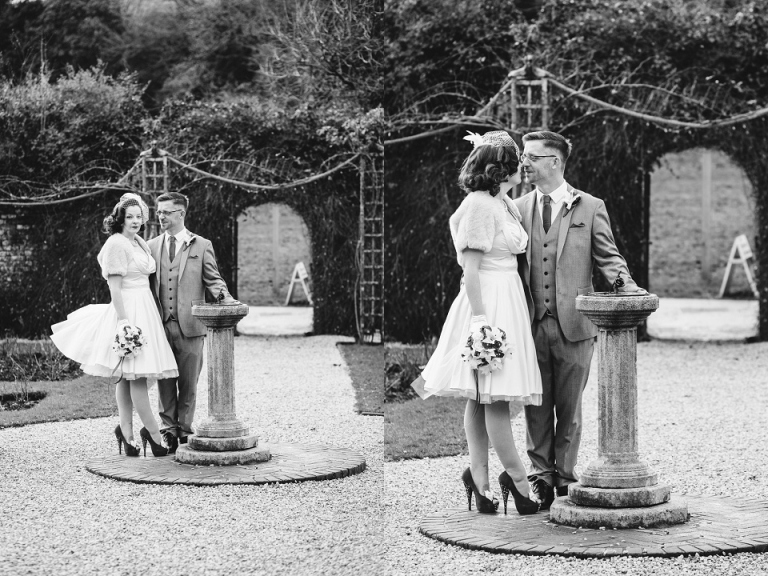 cockington court rose garden portraits, wedding dress blowing in the wind as they stand by sundial