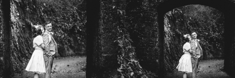 black and white of bride holding husband from behind under bridge at cockington