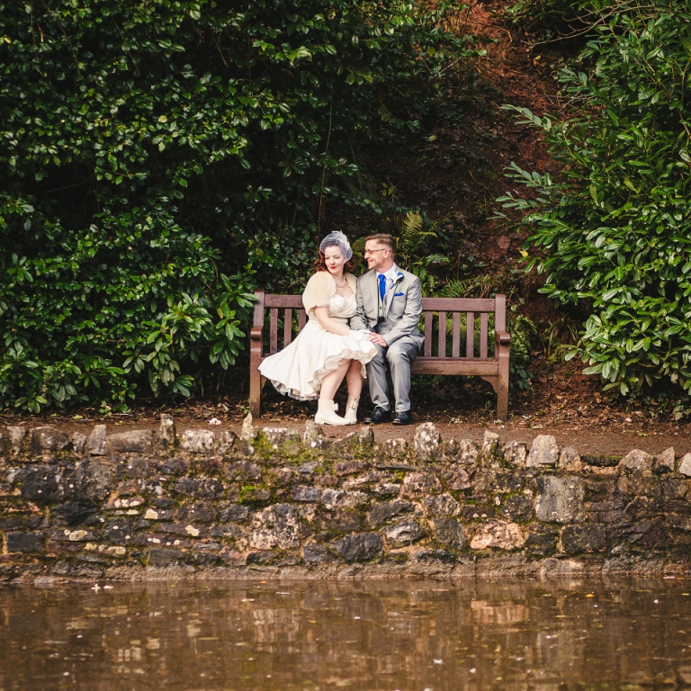 eloping couple sitting on bench by a river in Torquay
