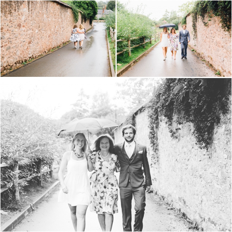 cockington-court-torquay-wedding-photography-documentary-style-2-brides-happy-walking-in-rain-under-umbrellas-to-ceremony